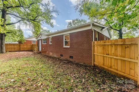 a backyard of a house with wooden fence and large trees