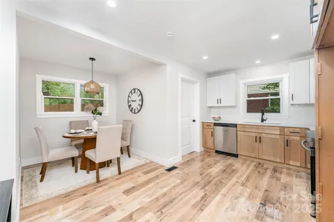 a large white kitchen with wooden floor and stainless steel appliances