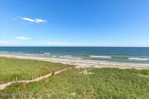 an aerial view of residential houses with outdoor space and ocean view