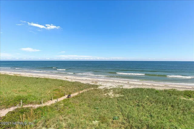 an aerial view of residential houses with outdoor space and ocean view