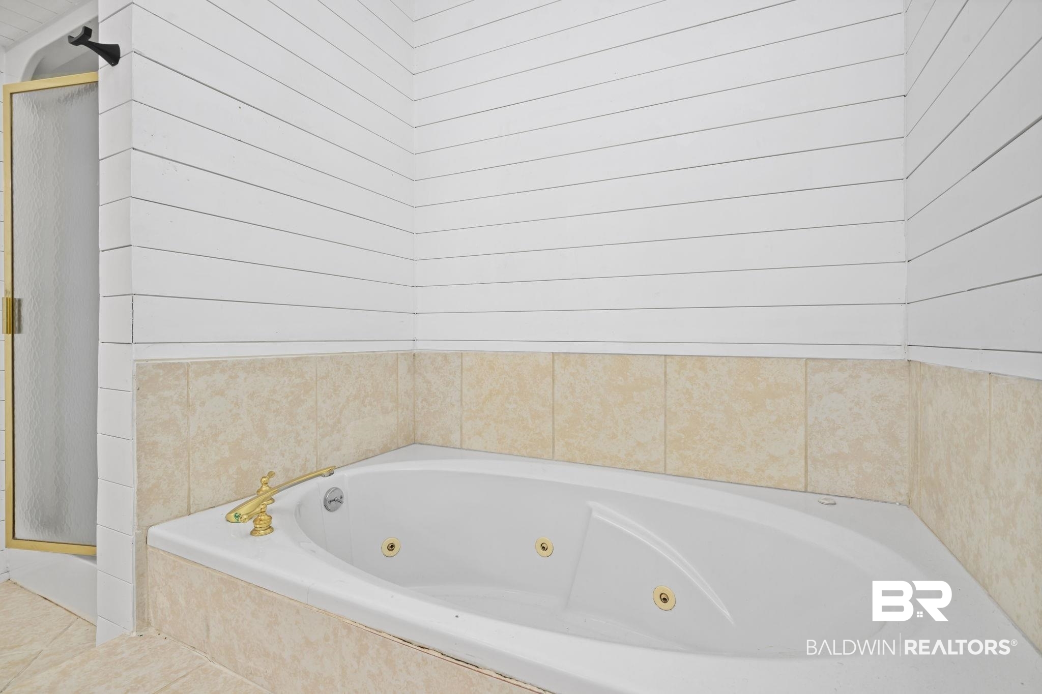 7540 2 Mile Road Irvington, AL 36544 - Photo 37 of 82 Corner soaking tub featuring gold-toned fixtures and jets, set within a tiled surround