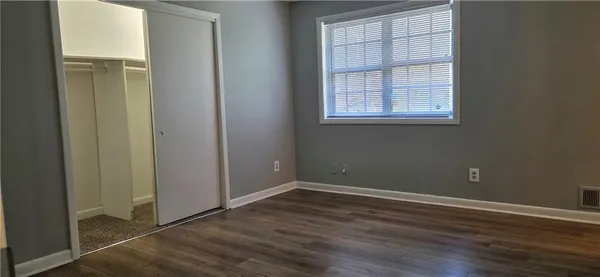 an empty room with wooden floor closet and windows