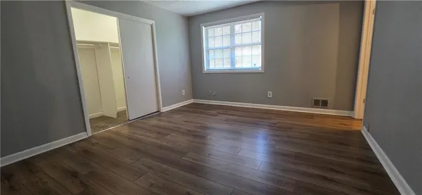 an empty room with wooden floor and windows