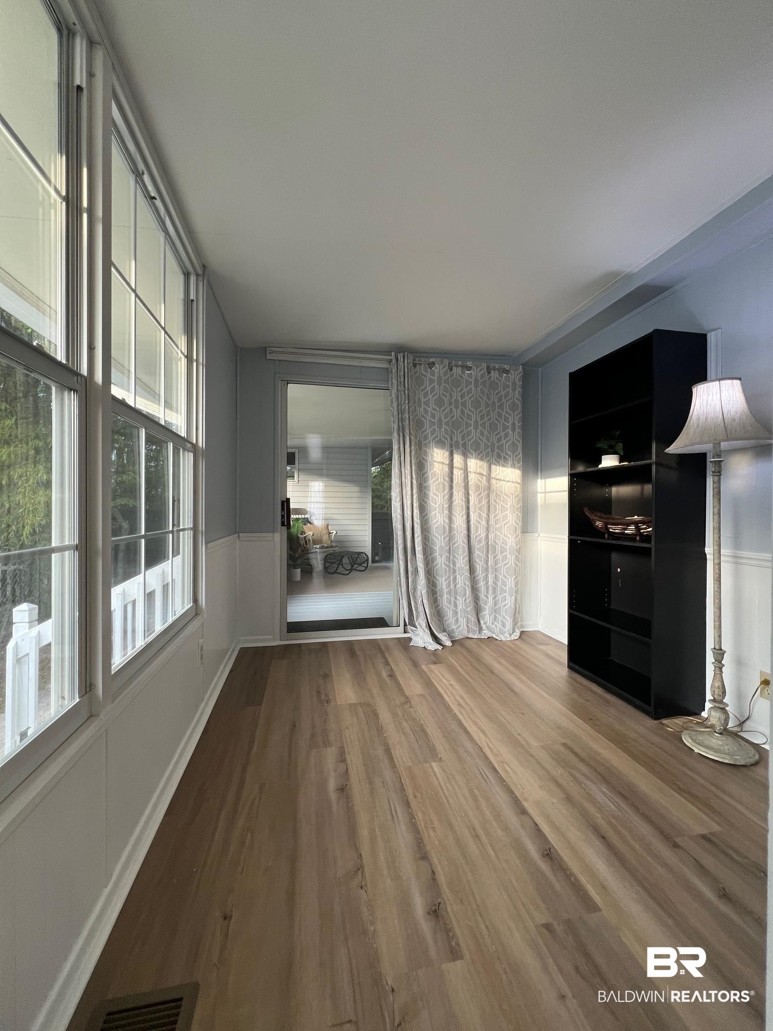 195 Defuniak Loop Lillian, AL 36549 - Photo 13 of 37 Unfurnished living room featuring visible vents, a decorative wall, wood finished floors, and wainscoting