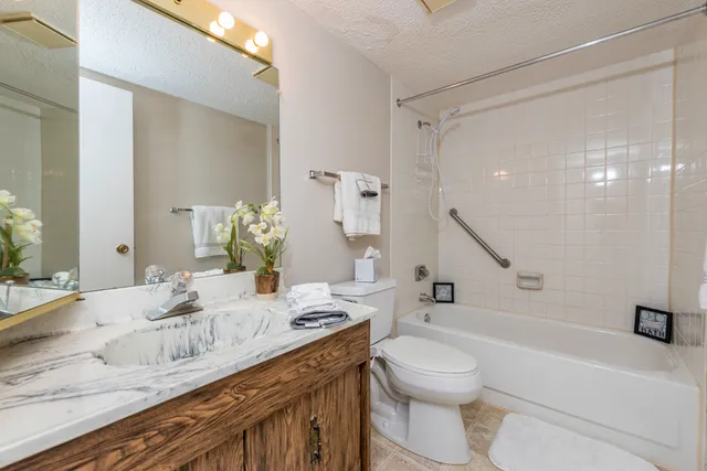 a bathroom with a granite countertop sink a toilet and a large mirror