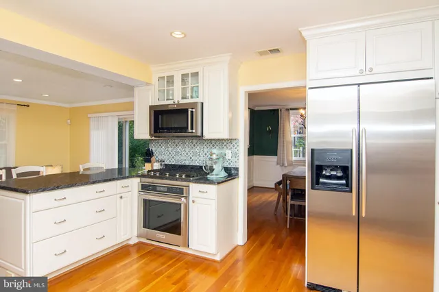 a kitchen with stainless steel appliances granite countertop a refrigerator a stove and a microwave