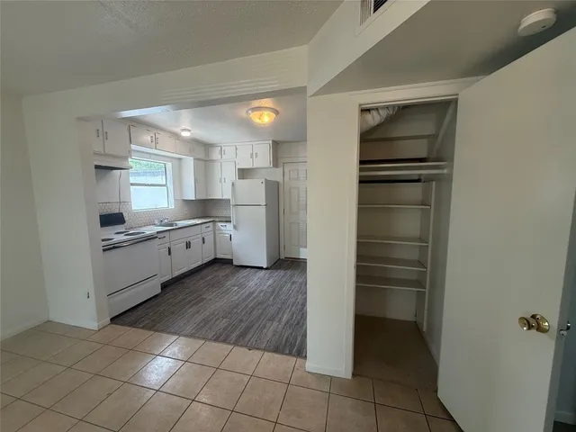 a kitchen with a refrigerator and white cabinets