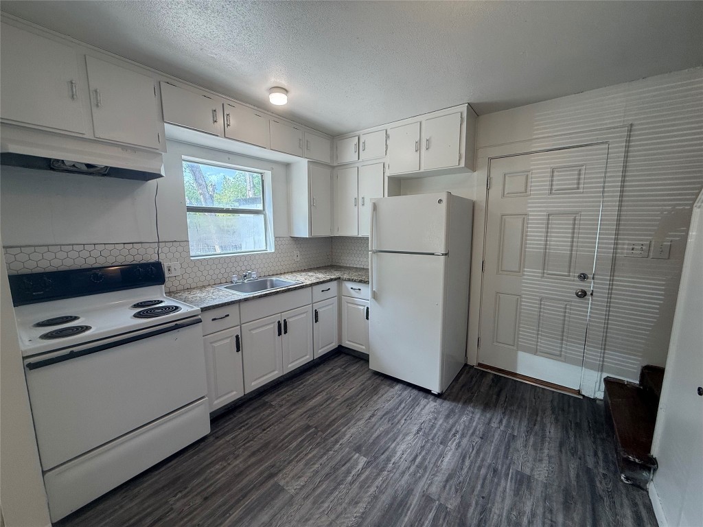622 Trinity Street Lockhart, TX 78644 - Photo 5 of 16 a kitchen with a refrigerator a stove top oven and wooden floors