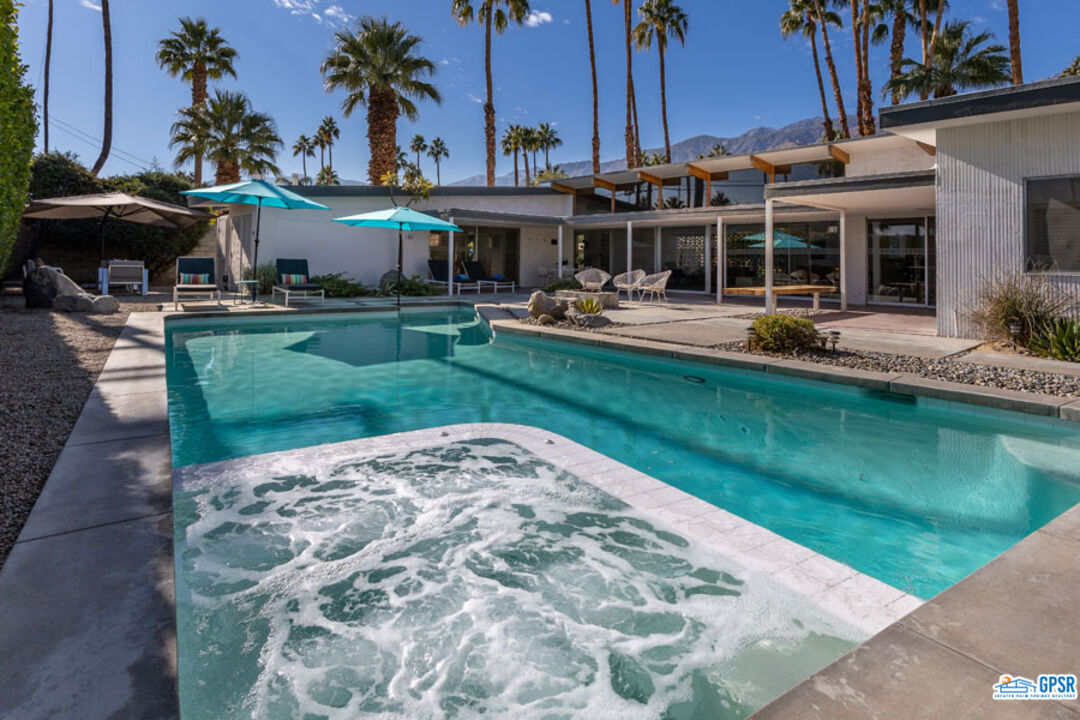 1090 Sagebrush Road Palm Springs, CA 92264 - Photo 20 of 49 a view of a swimming pool with a table and chairs under an umbrella