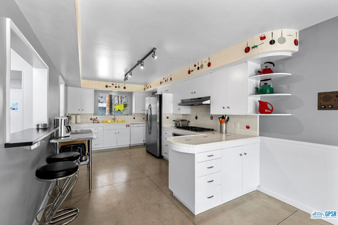 1090 Sagebrush Road Palm Springs, CA 92264 - Photo 23 of 49 a kitchen with white cabinets and appliances