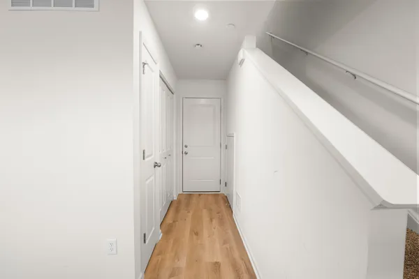 a view of a hallway with wooden floor and staircase