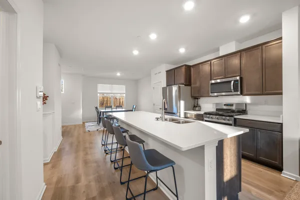 a kitchen with kitchen island wooden cabinets a stove a microwave a island with a dining table and chairs