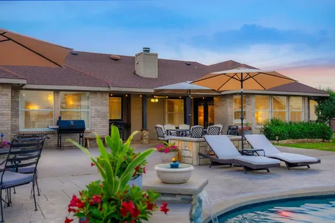 a view of a patio with couches table and chairs under an umbrella