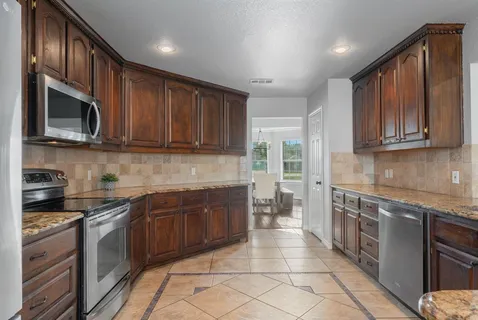 a kitchen with stainless steel appliances granite countertop wooden cabinets a stove top oven a sink and dishwasher