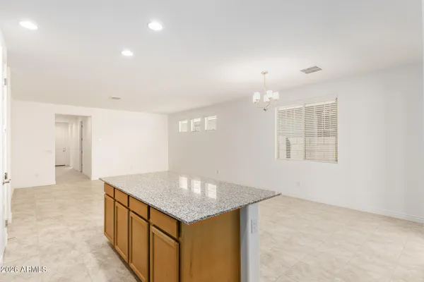 an empty room with kitchen view and windows