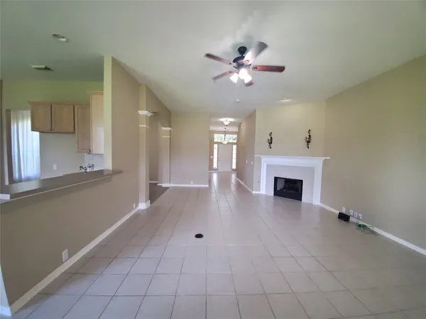 a view of an empty room with chandelier fan and fire place