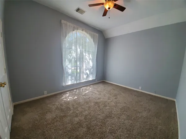 an empty room with a chandelier fan and windows