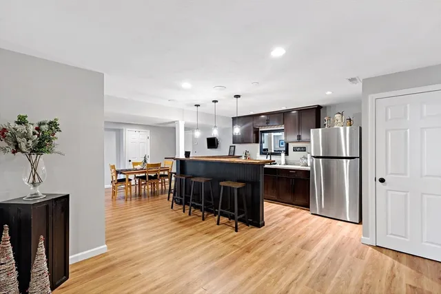 a kitchen with stainless steel appliances kitchen island granite countertop a refrigerator a stove a sink a dining table and chairs with wooden floor
