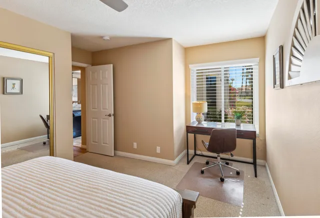 a bedroom with a bed a chair and a large window