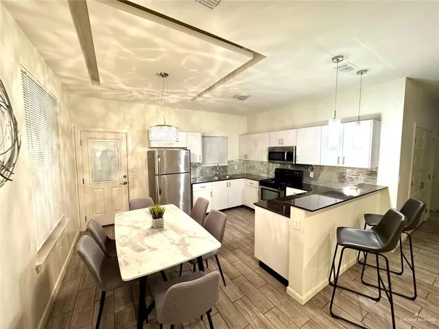 a kitchen with stainless steel appliances kitchen island granite countertop a table chairs and a refrigerator