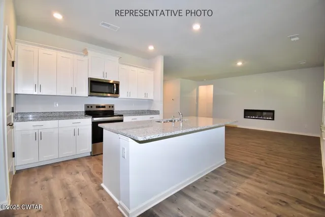 a large kitchen with stainless steel appliances a sink a stove and cabinets