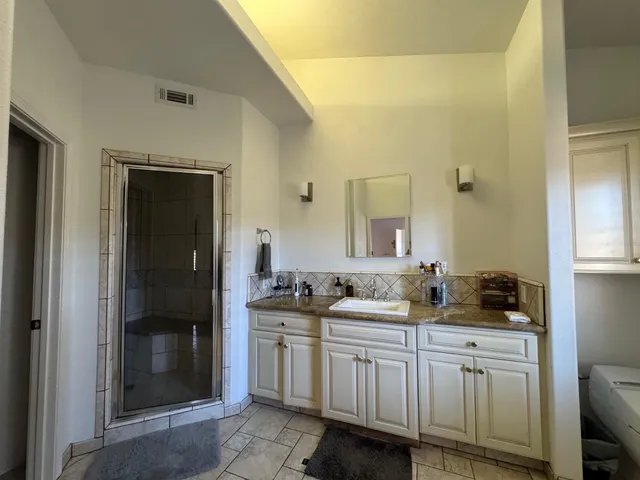 a view of a hallway with wooden floor and a bathroom