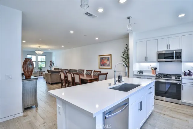 a kitchen with stainless steel appliances kitchen island a stove a sink a refrigerator and a refrigerator