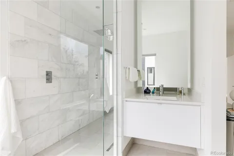 a bathroom with a granite countertop sink a mirror and shower