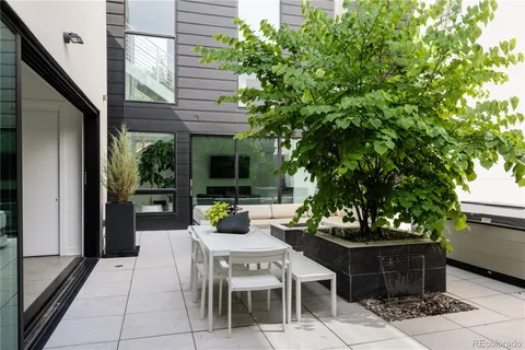 a view of a patio with table and chairs potted plants and floor to ceiling window