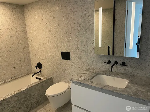 a bathroom with a granite countertop sink toilet and mirror