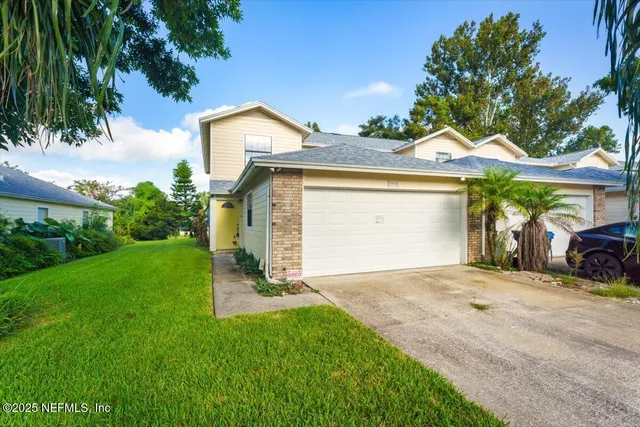 a view of a house with a small yard and a large tree