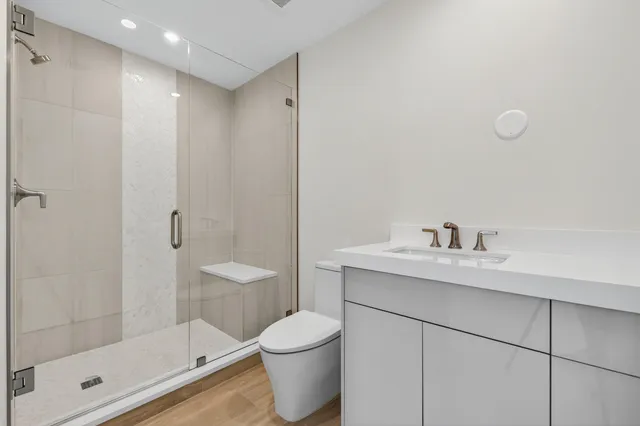 a bathroom with a granite countertop sink a toilet and shower