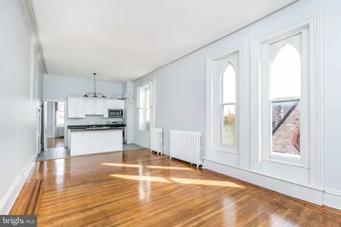 a view of a kitchen with kitchen island wooden floor and stainless steel appliances