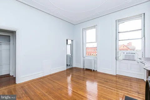 a view of an empty room with wooden floor and a fireplace