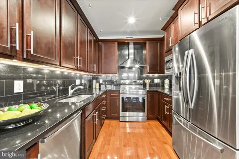 a kitchen with stainless steel appliances granite countertop a sink a stove and refrigerator