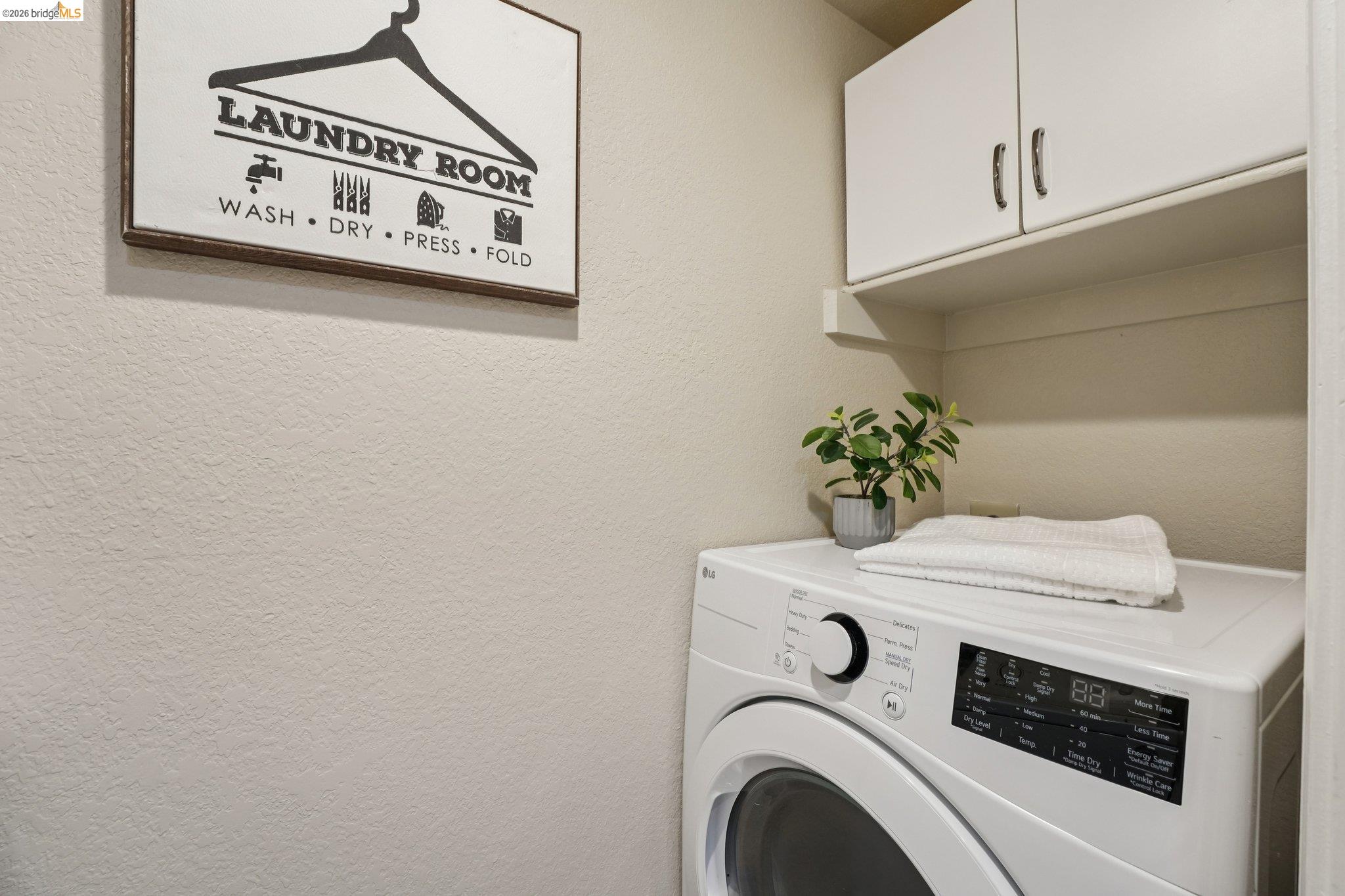 535 Pierce Street, Unit 3216 Albany, CA 94706 - Photo 26 of 47 Laundry room featuring washer / clothes dryer, cabinet space, and a textured wall