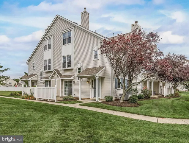 a view of a white house next to a yard with big trees
