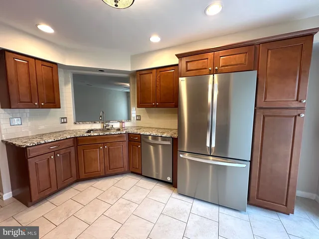 a kitchen with granite countertop stainless steel appliances a refrigerator and cabinets