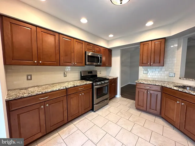 a kitchen with stainless steel appliances granite countertop wooden cabinets a stove top oven a sink and dishwasher