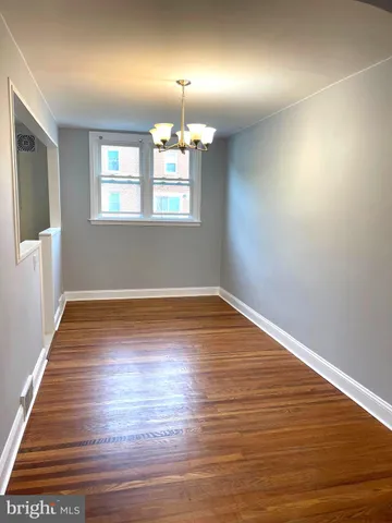 an empty room with wooden floor chandelier and windows