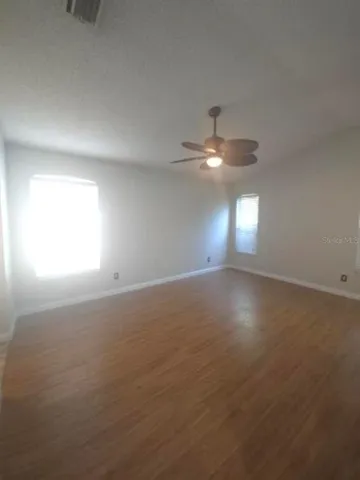 en empty room with windows and ceiling fan