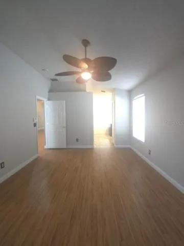 a view of empty room with wooden floor and fan