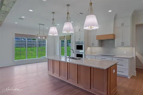 a kitchen with kitchen island granite countertop a stove a sink a oven and a wooden floors