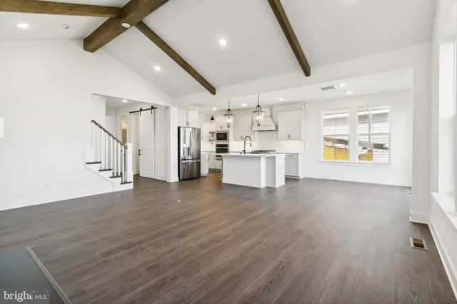 a view of a electric appliances in kitchen and empty room with wooden floor