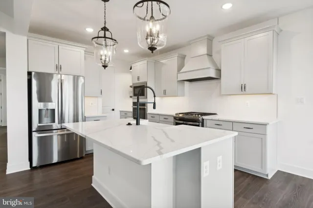 a kitchen with stainless steel appliances a sink a stove a refrigerator cabinets and wooden floor