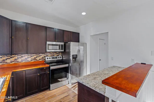 a kitchen with stainless steel appliances granite countertop a stove a sink and a refrigerator