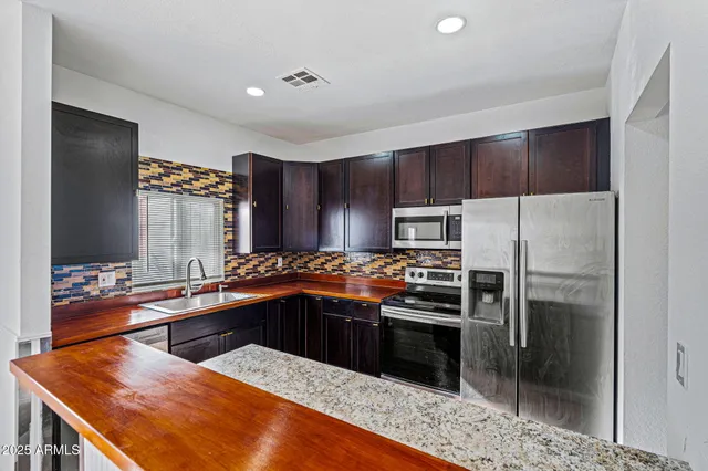 a kitchen with stainless steel appliances kitchen island granite countertop a sink stove and refrigerator