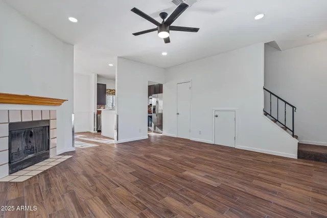 a view of an empty room with wooden floor a fireplace and a window