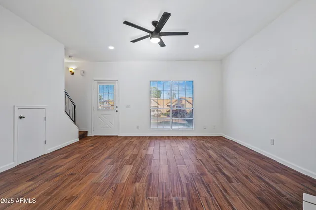 an empty room with wooden floor and ceiling fan