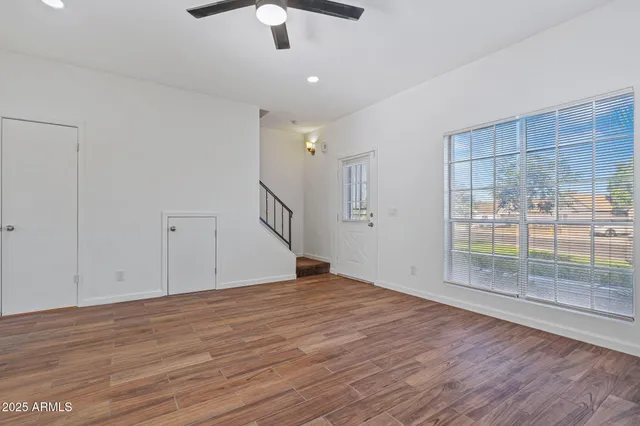 a view of an empty room with wooden floor and a window